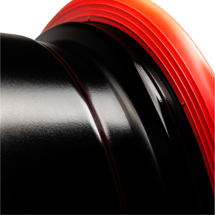 Image of a RIMFINITY continious rubber band wheel protector in red, on a bare black alloy wheel rim. Image shows ridges in the design and no joins.