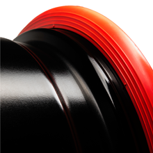 Load image into Gallery viewer, Close-up of red RIMFINITY continuous rubber band technology fitted to a bare, black alloy wheel rim
